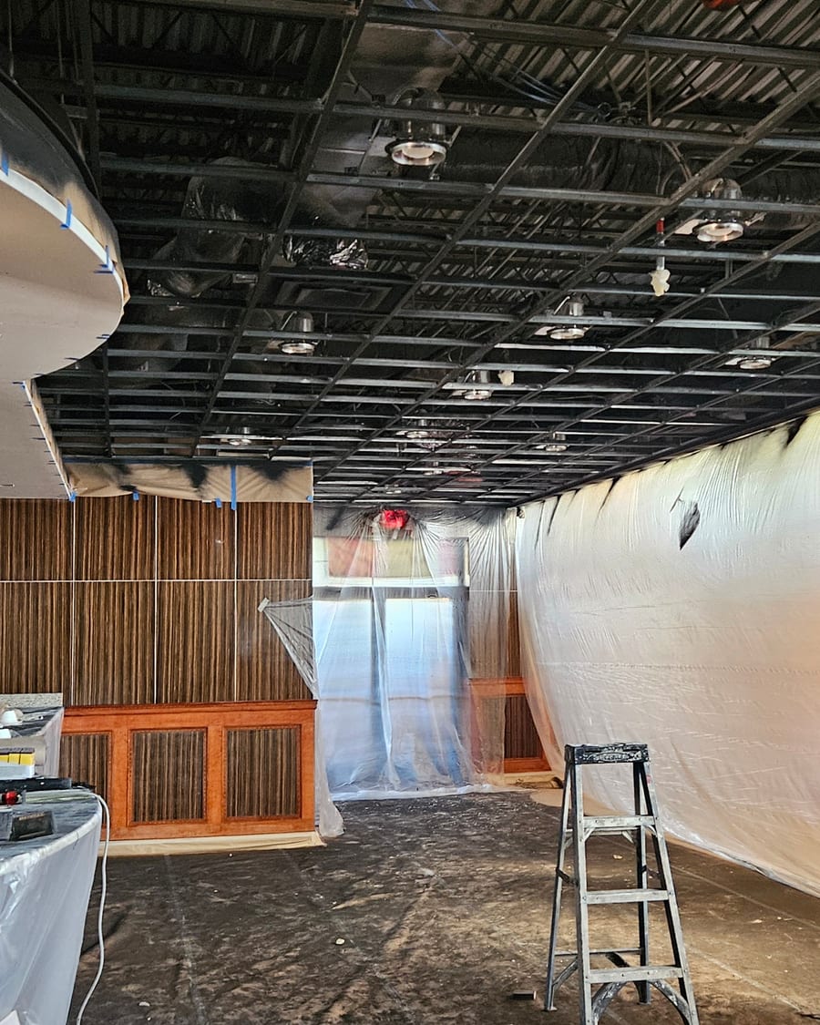 The dining room stripped back during renovation — exposed ceiling and protective sheeting