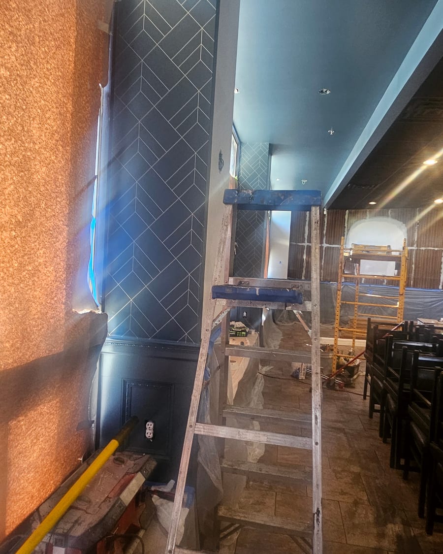 A dark patterned feature wall going in as the finishes begin